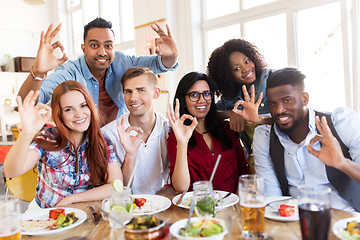 Image showing happy friends showing ok hand sign at restaurant