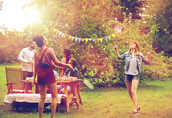 Image showing happy friends playing badminton at summer garden