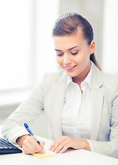 Image showing businesswoman writing on sticky note