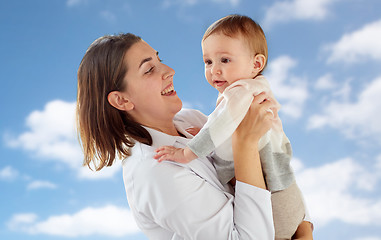 Image showing happy doctor or pediatrician with baby over sky