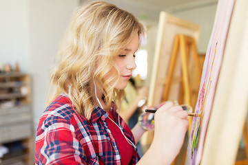 Image showing student girl with easel painting at art school