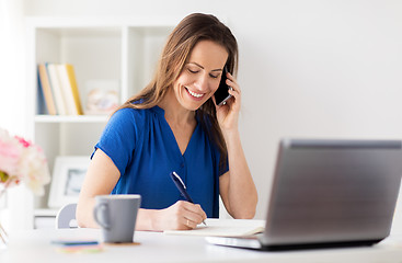 Image showing woman with notepad calling on smartphone at office