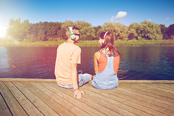 Image showing teenage couple with headphones on river berth