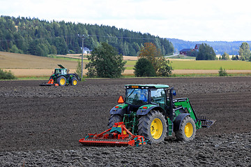 Image showing Two John Deere Tractors Cultivating Field