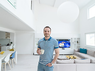 Image showing young man drinking morning coffee by the window