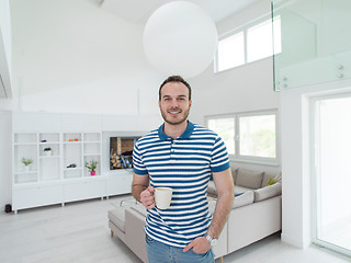 Image showing young man drinking morning coffee by the window