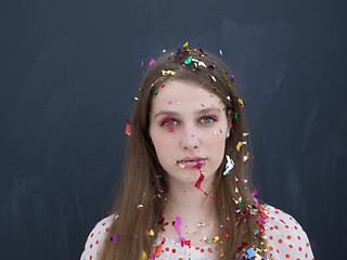 Image showing woman blowing confetti in the air isolated over gray