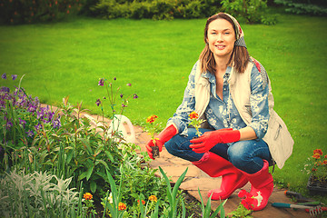 Image showing smiling woman in kerchief and red boots planting flowers