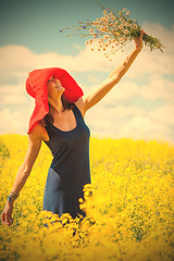 Image showing joyful woman in a red hat with a bouquet of wild flowers