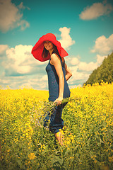 Image showing happy woman in a red hat with a bouquet of wildflowers