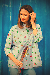 Image showing Portrait of a beautiful smiling woman with a guitar 