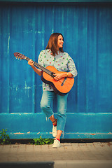 Image showing Beautiful smiling woman in jeans playing guitar 