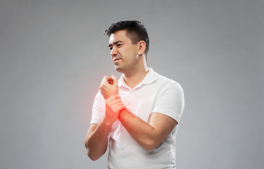 Image showing unhappy man suffering from pain in hand