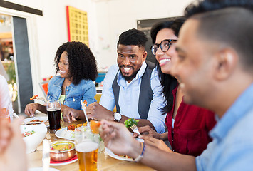 Image showing happy friends eating and talking at restaurant