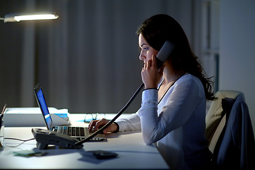 Image showing woman with laptop calling on phone at night office