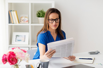 Image showing woman in glasses reading newspaper at office