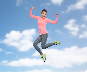 Image showing happy smiling sporty young woman jumping in sky
