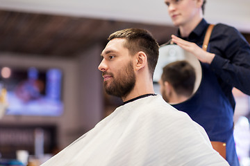 Image showing man and hairdresser with mirror at barbershop