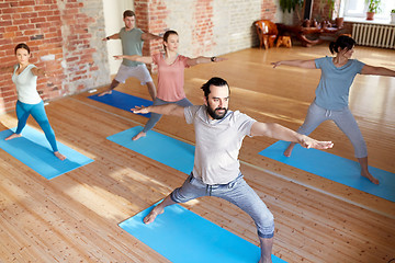 Image showing group of people doing yoga warrior pose at studio