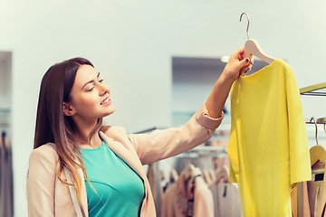 Image showing happy young woman choosing clothes in mall