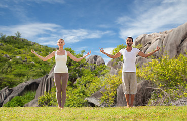 Image showing happy couple making yoga exercises on beach