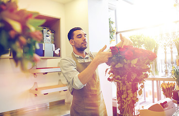 Image showing smiling florist man with roses at flower shop