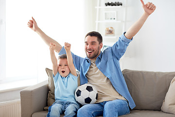 Image showing father and son watching soccer on tv at home