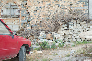 Image showing Old rusty red car parked near the wall