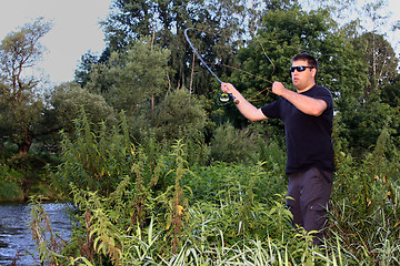 Image showing Young man with fishing rod fishing at a river