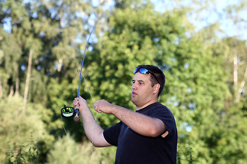 Image showing Young man with fishing rod fishing at a river