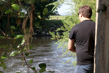 Image showing Young man with fishing rod fishing at a river