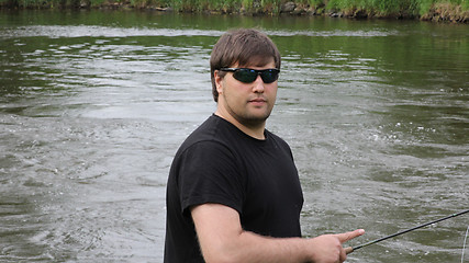 Image showing Young man with fishing rod fishing at a river