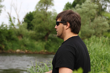 Image showing Young man with fishing rod fishing at a river