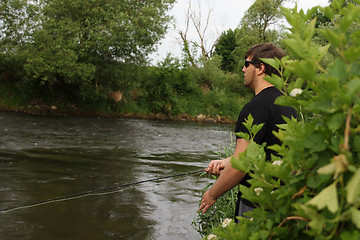 Image showing Young man with fishing rod fishing at a river