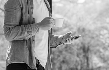 Image showing Clouseup of young man using mobile and drinking coffe