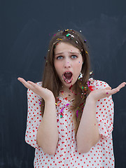 Image showing woman blowing confetti in the air isolated over gray