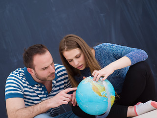 Image showing couple in casual clothing investigating globe