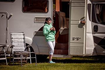 Image showing Woman is standing with a mug of coffee near the camper.