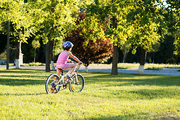 Image showing happy child girl riding bicycle in summer sunset