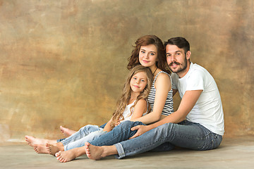 Image showing Pregnant mother with teen daughter and husband. Family studio portrait over brown background