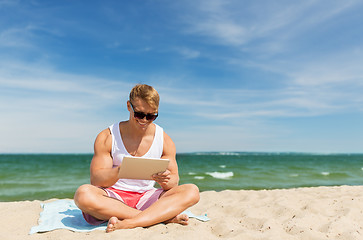 Image showing happy smiling young man with tablet pc on beach