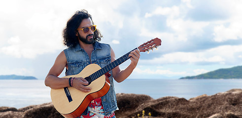 Image showing hippie man playing guitar over sea