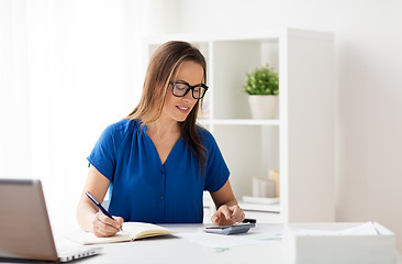 Image showing woman with calculator and notebook at office