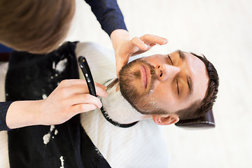 Image showing man and barber with straight razor shaving beard