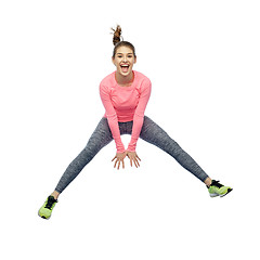 Image showing happy smiling sporty young woman jumping in air