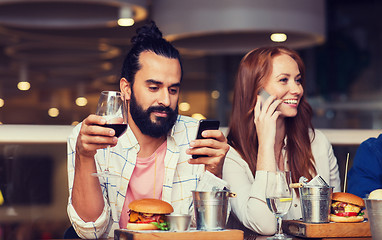 Image showing happy friends with smartphones at restaurant