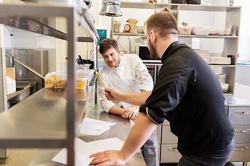 Image showing chef and cook with grocery list at kitchen