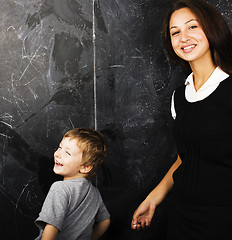Image showing little cute boy with young teacher in classroom studying at blac