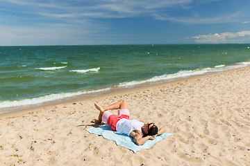 Image showing happy smiling young man sunbathing on beach towel