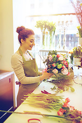 Image showing smiling florist woman making bunch at flower shop